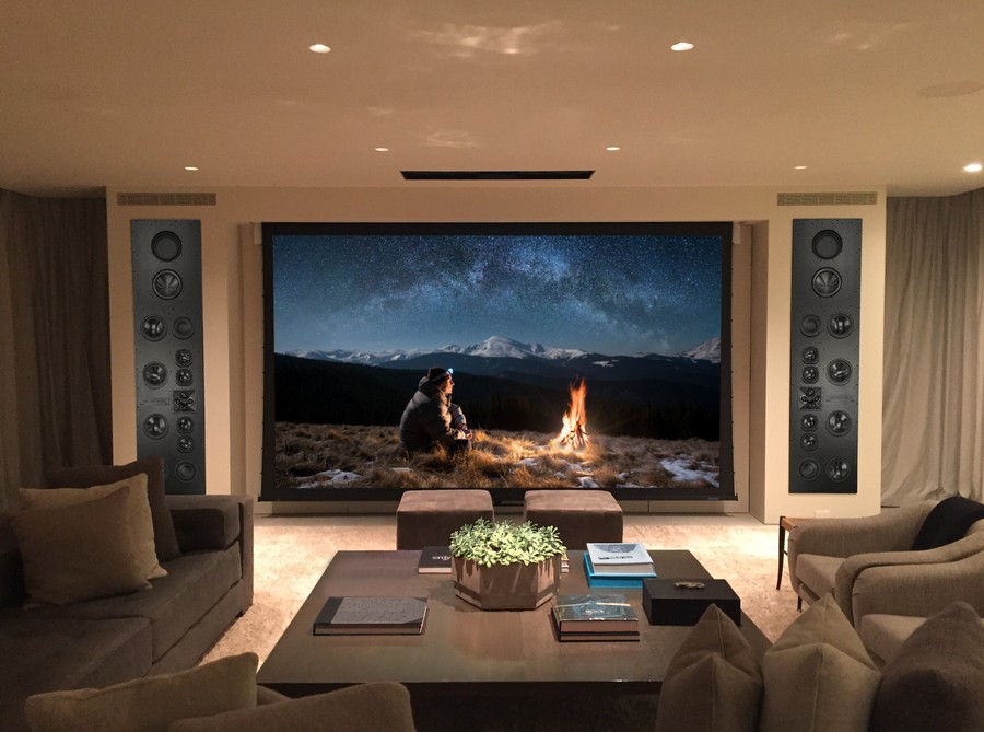 A media room with in-ceiling speakers, a large screen, and James Loudspeakers on either side.