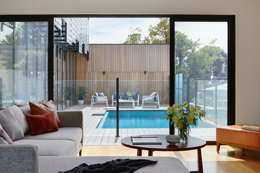 Elegant and sunny living room looks out over modernist architecture and pool. 