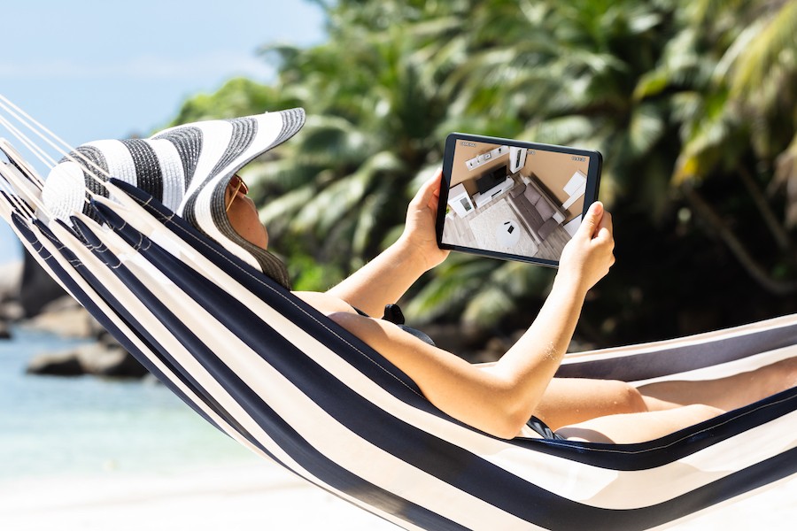 Woman in hammock is checking home security videos on a tablet.