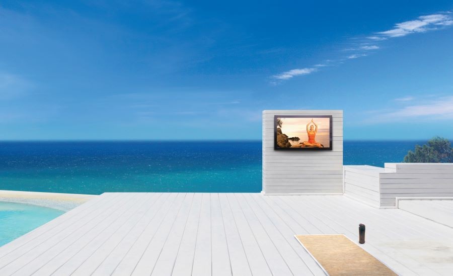 An outdoor area next to the ocean with an outdoor TV and a yoga mat.