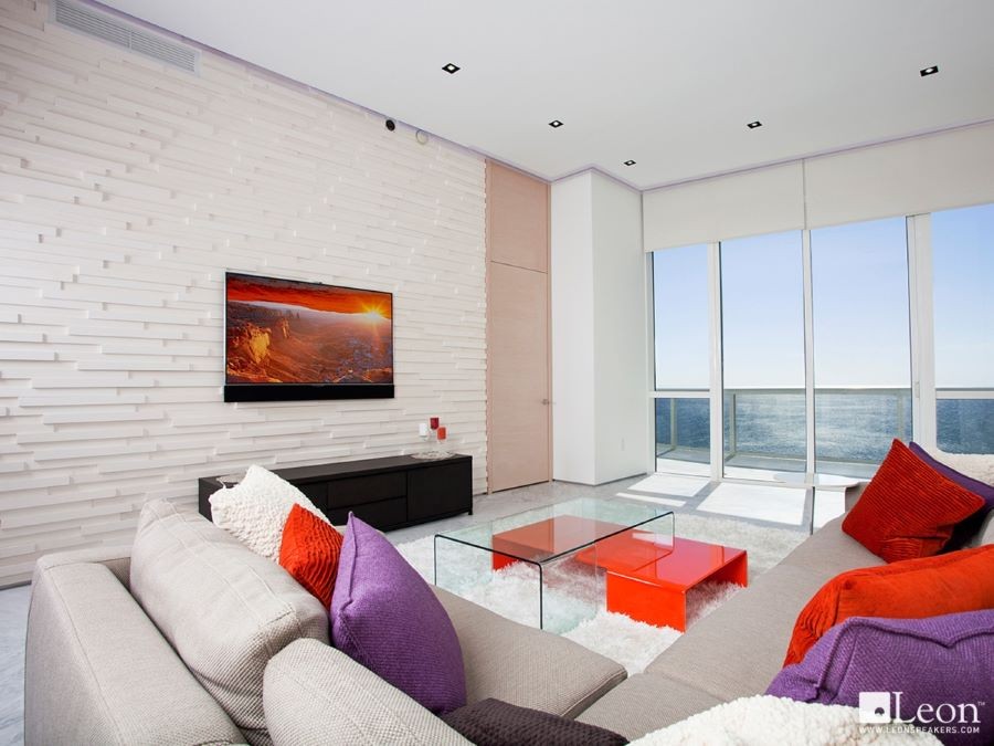 A modern living room looking out over the ocean with in-ceiling speakers.
