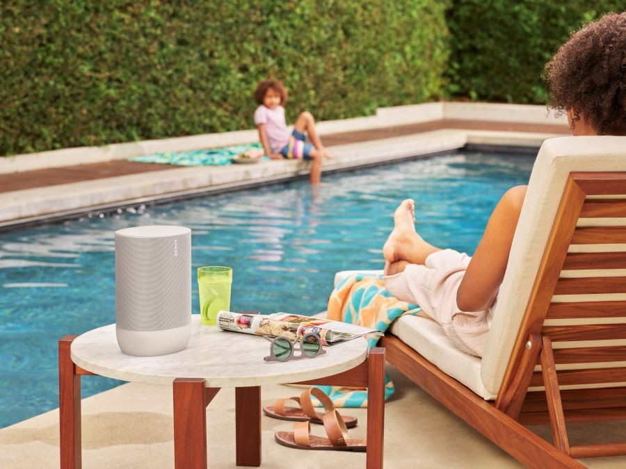 People sitting by a pool with a Sonos Move outdoor speaker on a side table. 