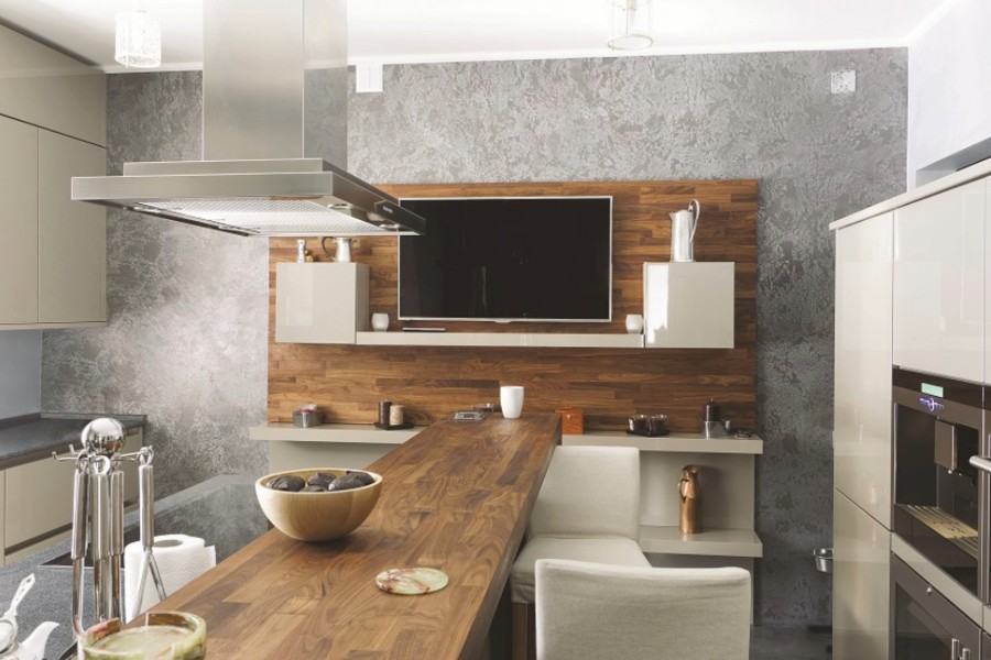 A modern kitchen featuring a spacious island and a TV.