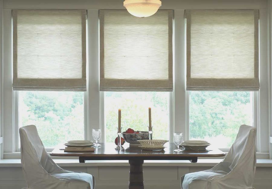 Lutron Roman shades in a dining area with multiple windows, creating a soft, elegant look.